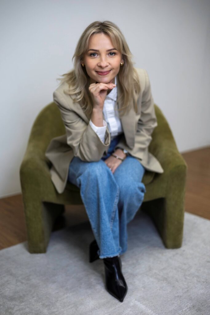 Monika Clayton, South London interior designer, seated in a neutral chair in a calm interior setting