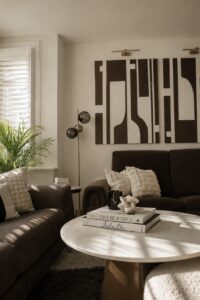 Contemporary living room with brown seating, abstract artwork and soft natural light through plantation shutters.