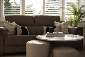 Contemporary living room with fireplace, bespoke shelving, dark accent chair and warm neutral colour palette.