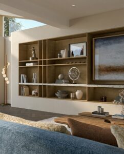 Calm neutral living room detail with a curved wood coffee table, soft blue sofa and layered decorative styling.